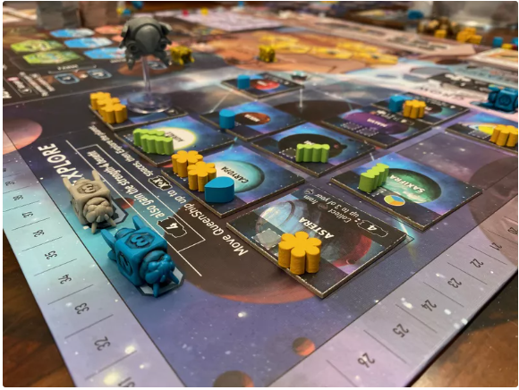 Close-up of a vibrant board game with a space theme. Colorful tokens and tiles cover the board, creating an engaging atmosphere for players.